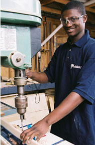 Young man working with a drill press.